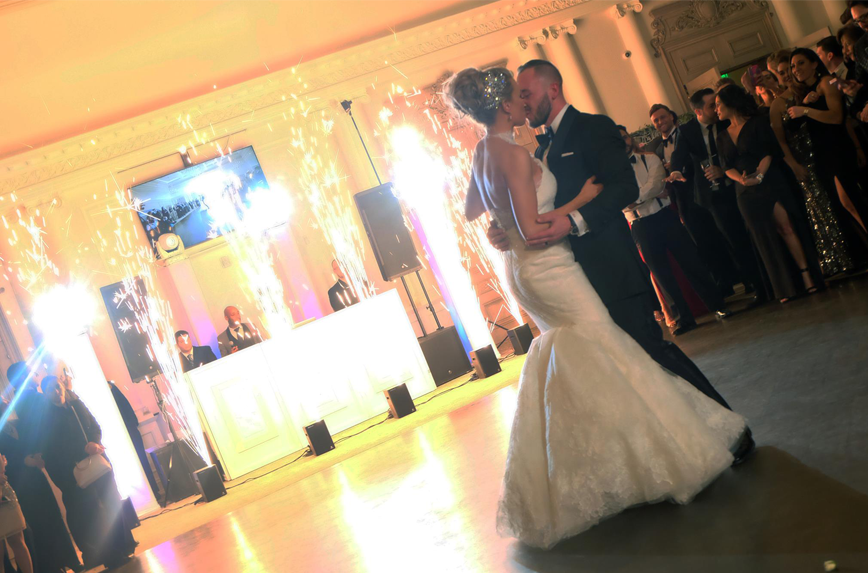 Bride and groom kiss while indoor fireworks set off