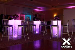 Lounge setup including LED purple lit high rise tables and tall metal stool chairs